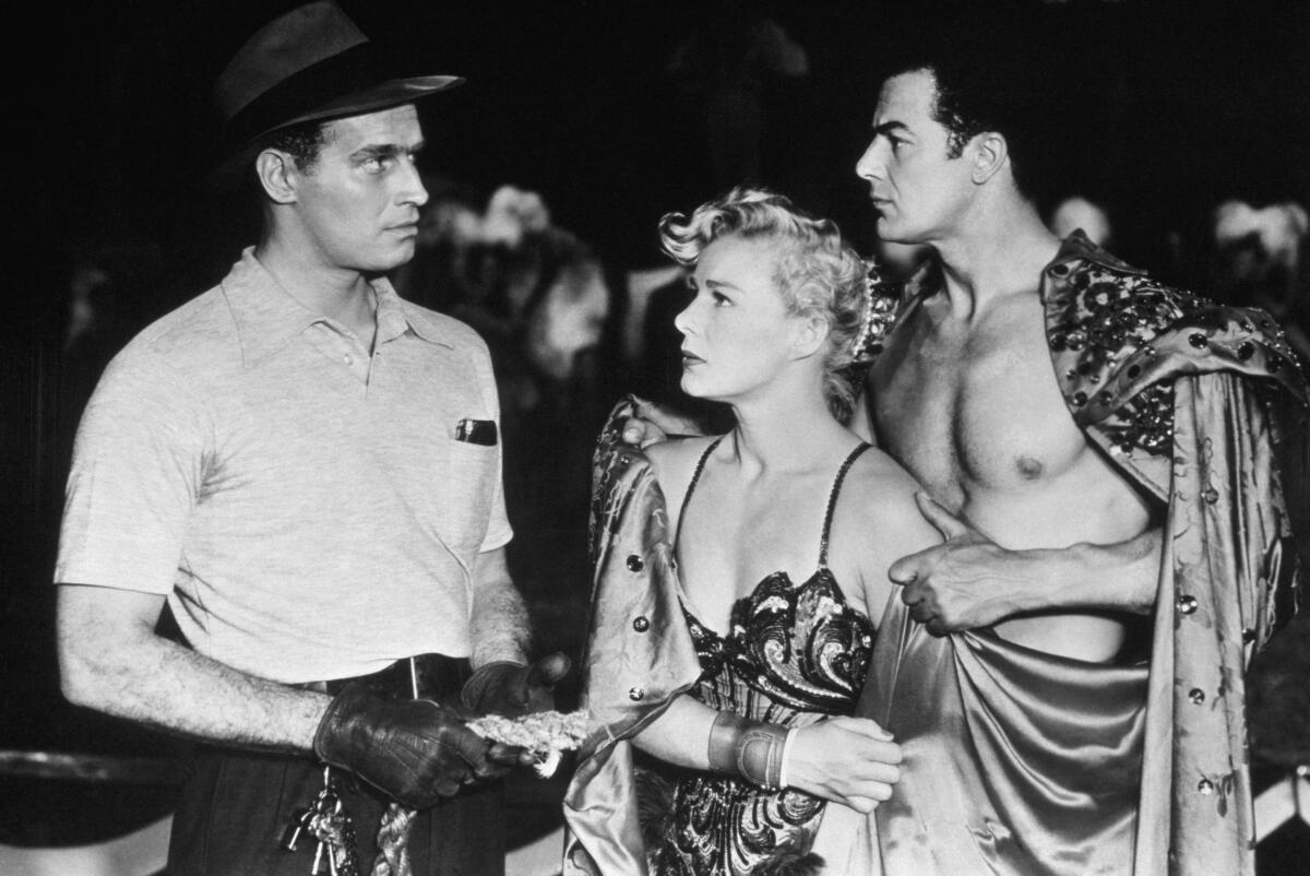 black and white photo of a man, left, and a scantily clad woman and man