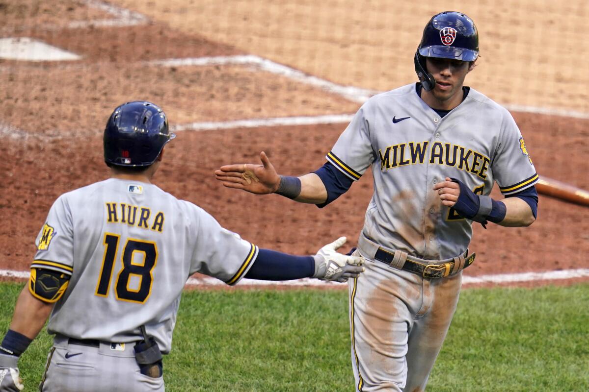Milwaukee Brewers' Christian Yelich, right, celebrates with Keston Hiura after scoring on a single by Milwaukee Brewers' Jace Peterson during the sixth inning of a baseball game against the Pittsburgh Pirates in Pittsburgh, Saturday, July 3, 2021. (AP Photo/Gene J. Puskar)
