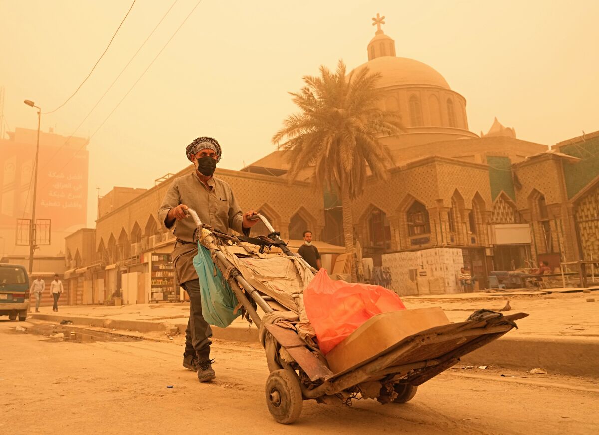 A man pushes a cart during a sandstorm in Baghdad, Iraq, Monday, May 16, 2022. (AP Photo/Hadi Mizban)