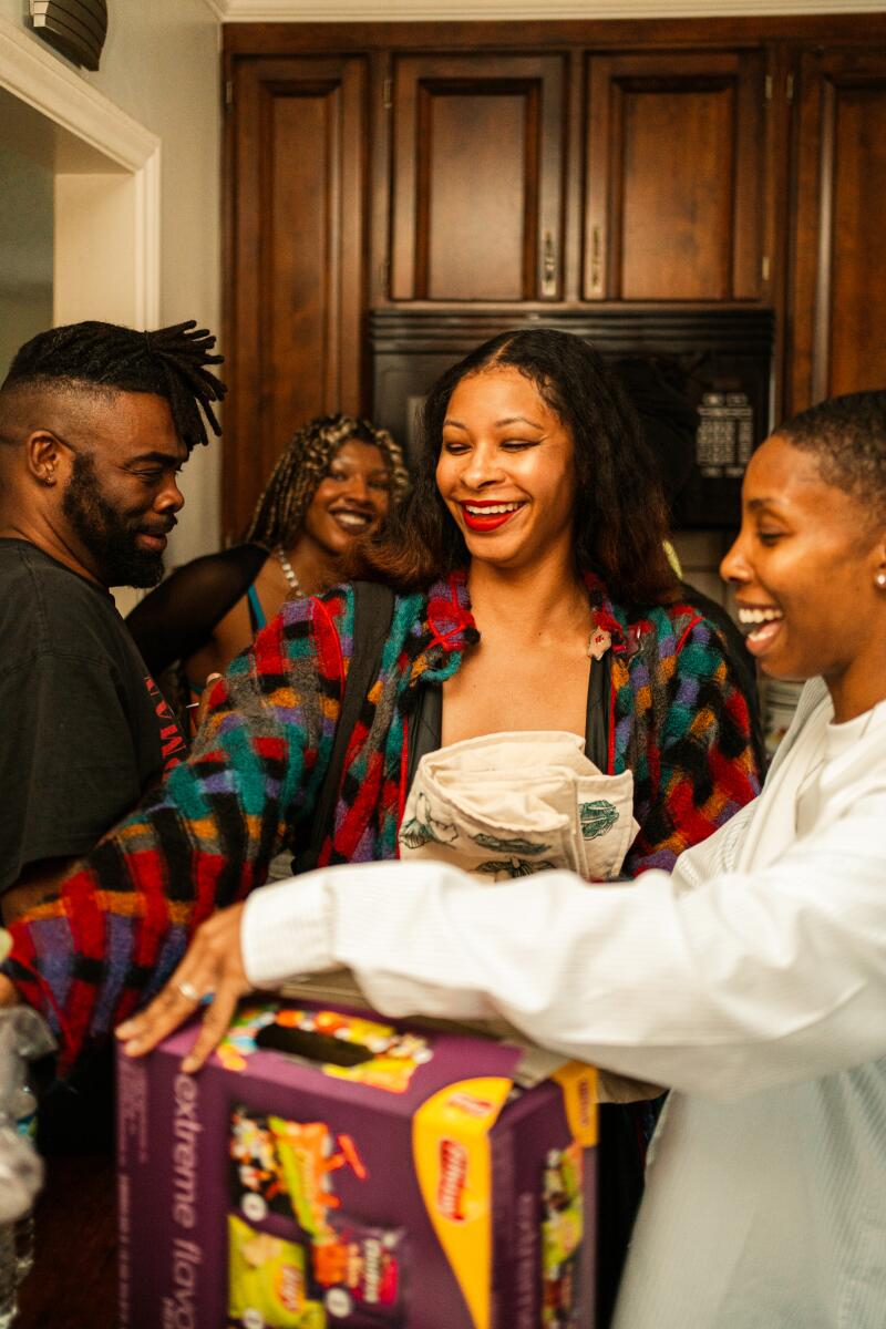 "Black House" Attendees socialize in the kitchen while eating slices of pizza and homemade cake.