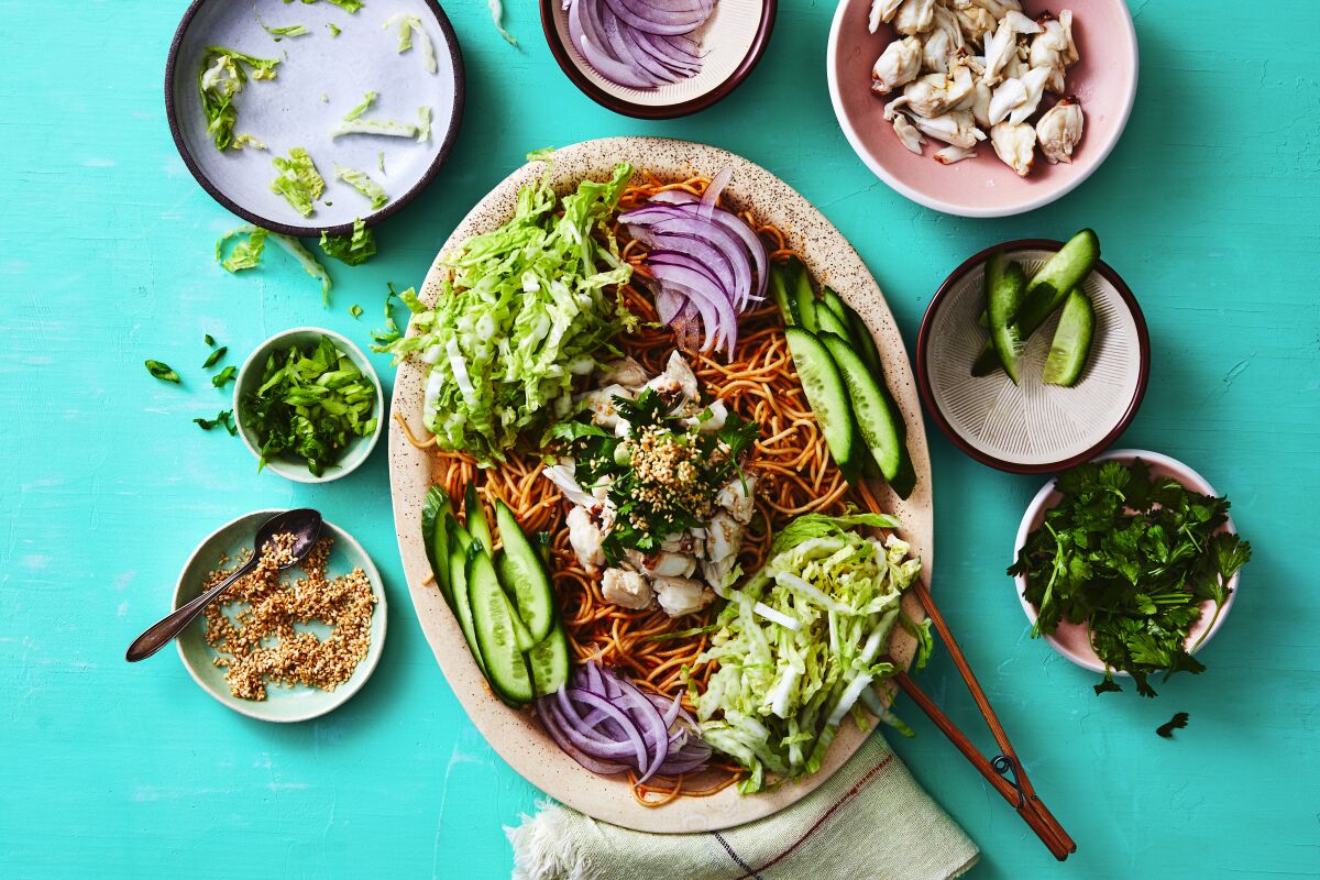 Sesame Cold Noodles with Crab and Crunchy Vegetables on an oval platter, surrounded by small dishes of vegetables