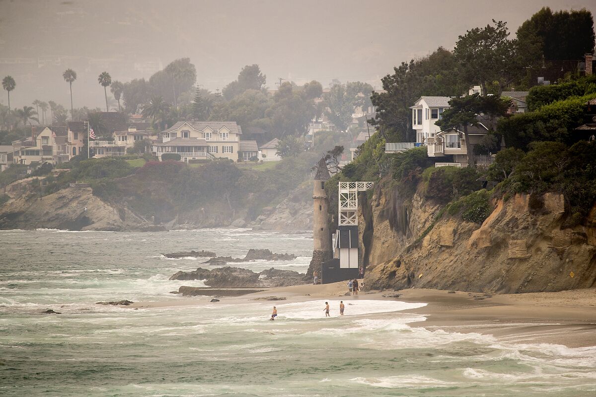 Beach-goers frolic in the water in front of a tower at Victoria Beach in Laguna Beach.