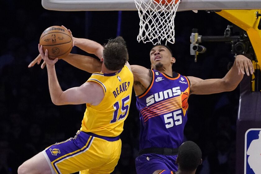 Austin Reaves (izquierda), de los Lakers de Los Ángeles, lanza a canasta ante Darius Bazley durante el juego de la NBA que enfrentó a su equipo con los Suns de Phoenix, el 22 de marzo de 2023, en Los Ángeles. (AP Foto/Mark J. Terrill)