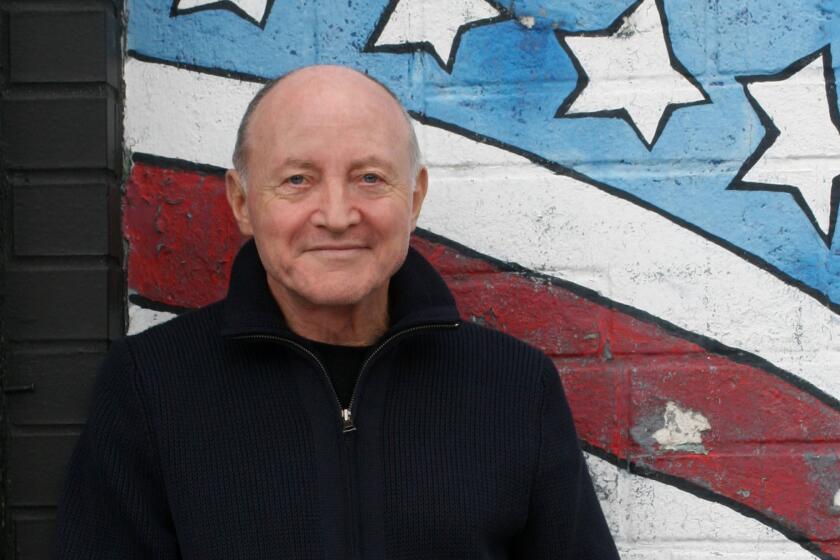 Sylvère Lotringer is shown standing before a mural of an American flag