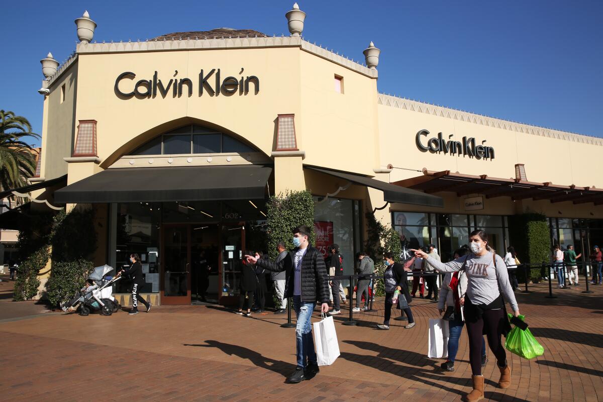 Shoppers wait in line to enter the Calvin Klein store at the Citadel Outlets in Commerce in December.