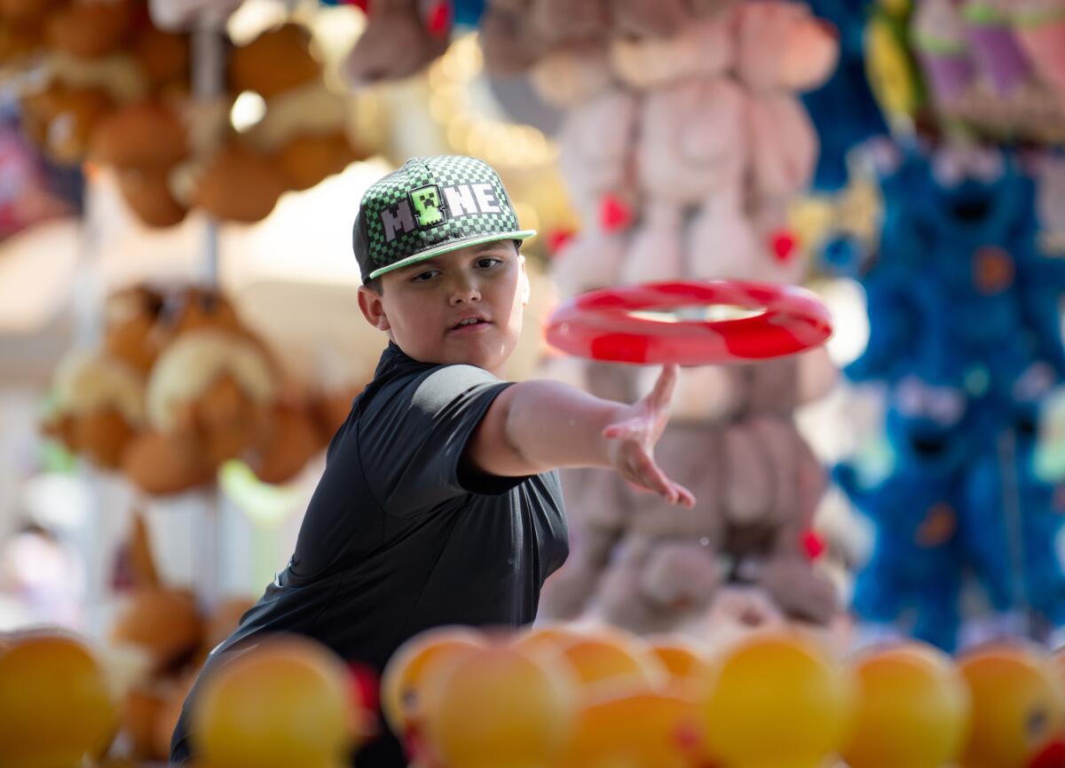 Adrian Silva tosses a ring at rubber ducks during opening day at the OC Fair on Friday.