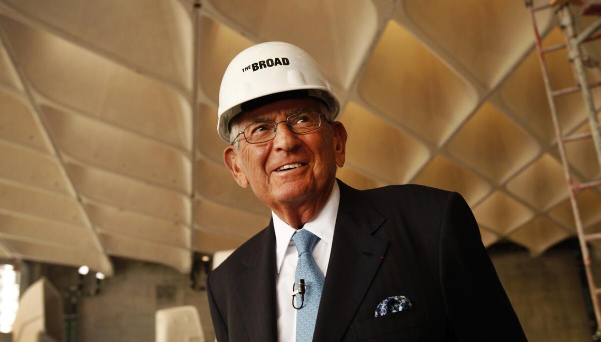 Eli Broad in a suit and a white hard hat in his under-construction museum