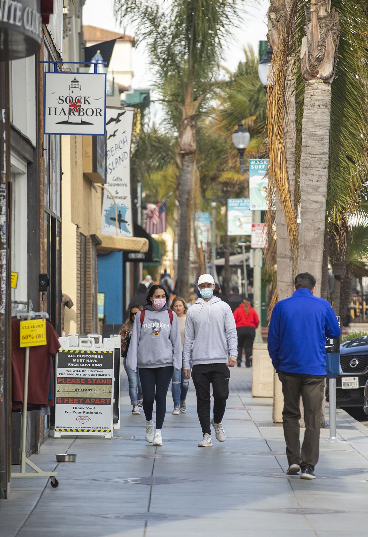 Pedestrians walk down Main Street in Huntington Beach on Monday, March 15.
