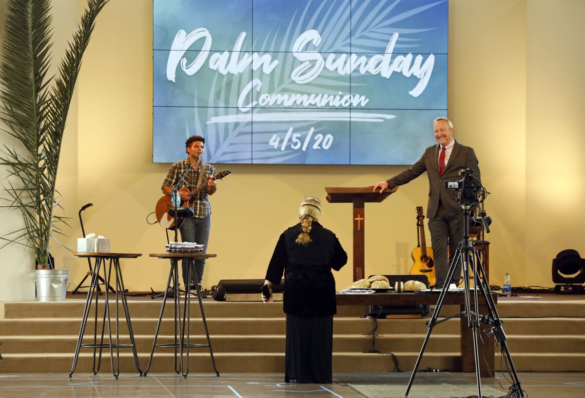 Pastor Rob McCoy, right, gives Communion at an April 5 Palm Sunday service at his Thousand Oaks church.