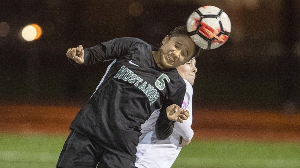 Costa Mesa's Daisy Carrillo (5) goes up for a header against Calvary Chapel's Isabella Beortegui in an Orange Coast League home match on Jan. 17.