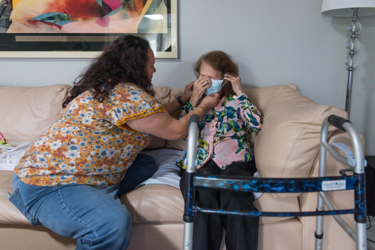 Gina Moran helps her mother put on a mask.