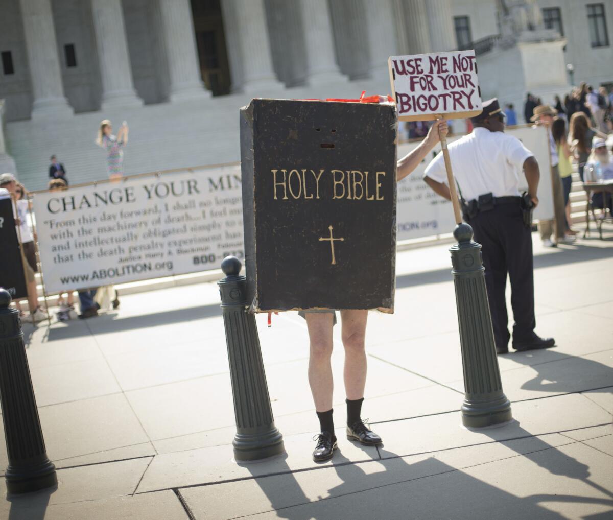 Your new health insurance guidebook? A demonstrator stands outside the Supreme Court building awaiting the Hobby Lobby ruling Monday.