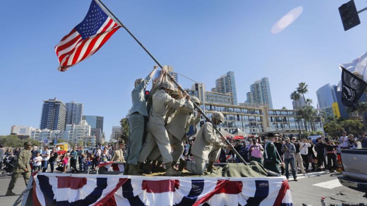 Marine Corps members reenact an iconic WWII photo on a parade float as a crowd looks on