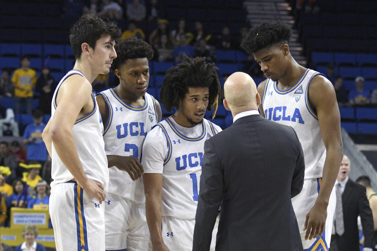 UCLA coach Mick Cronin speaks with players Jaime Jaquez Jr., David Singleton, Tyger Campbell and Chris Smith.