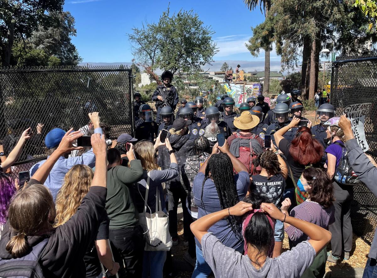 a group of people crowd near a fence opening