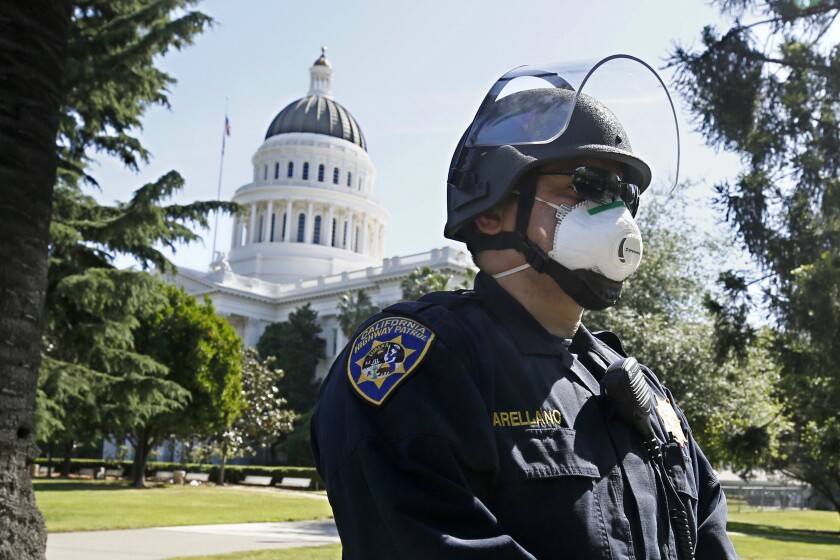 FILE - In this May 7, 2020, file photo, California Highway Patrol Officer S. Arellano wears a face mask as he and other officers form a line around at anticipation of a protest rally at the the state Capitol in Sacramento, Calif. On Tuesday, July 6, 2021, the mask mandate was reinstated for all legislators and staff entering the Capitol regardless of their vaccination status after nine new COVID-19 cases was reported last week. (AP Photo/Rich Pedroncelli, File)