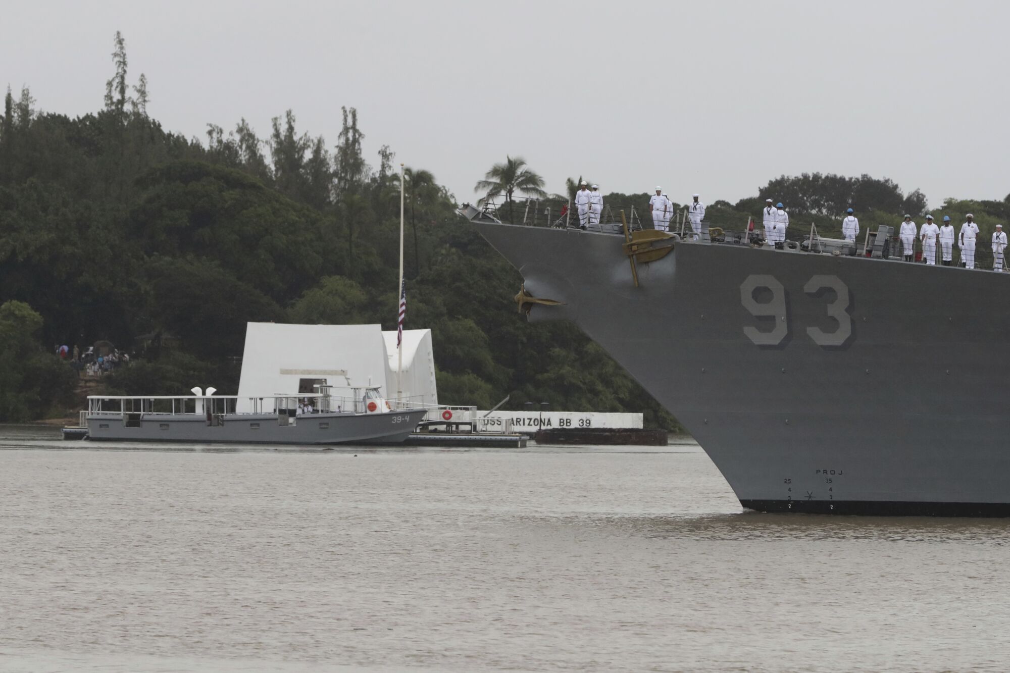 The USS Chung Hoon passes  the USS Arizona Memorial during the anniversary ceremony