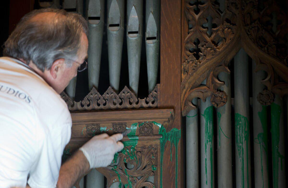 William Adair of Gold Leaf Studios removes green paint from the organ in the Washington National Cathedral's historic Bethlehem Chapel in Washington. The paint was splashed onto the organ and on the floor inside the chapel in the basement level and inside Children's Chapel in the nave of the cathedral.