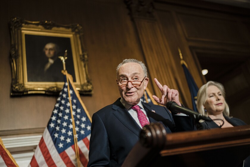Charles Schumer speaks at a lectern alongside Kirsten Gillibrand