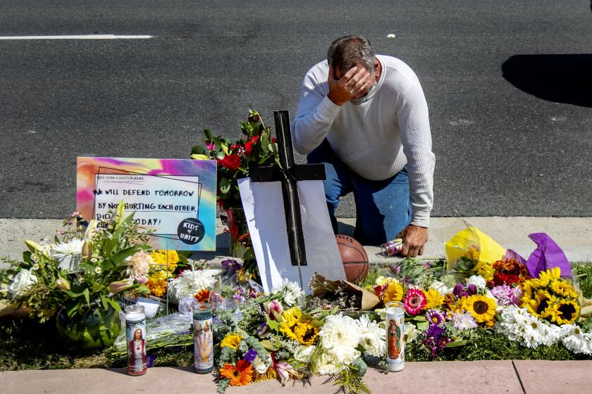 SAN CLEMENTE, CA - SEPTEMBER 25, 2020: Danny Blain is overcome with emotion as he kneels at a memorial for Kurt Andras Reinhold, a homeless Black man who was shot by Orange County deputies last week after they stopped him for jay walking and a scuffle ensued near Hotel Miramar on September 25, 2020 in San Clemente, California. (Gina Ferazzi / Los Angeles Times)