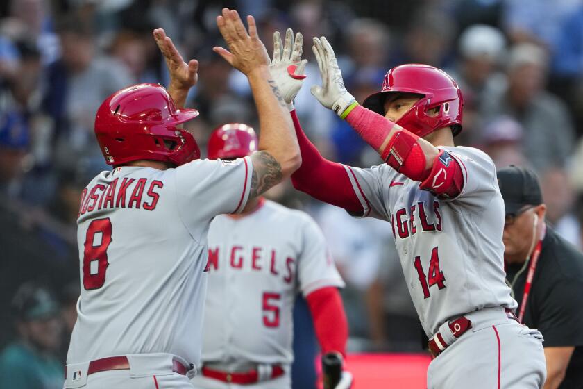 Los Angeles Angels' Logan O'Hoppe (14) is greeted by teammate Mike Moustakas (8) after scoring.