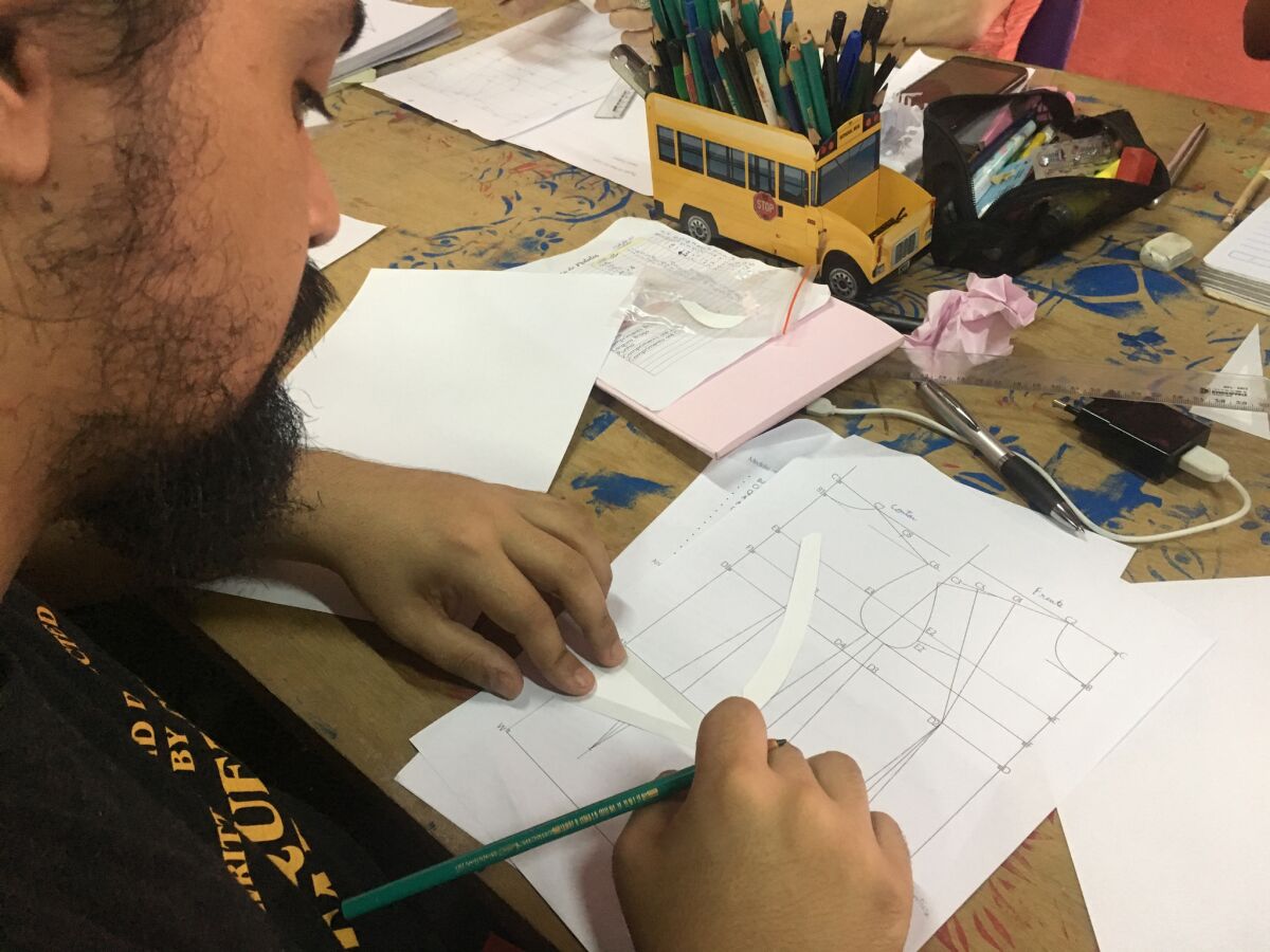 Max Milliano Melo, a student in Casa 1's sewing class, learns to draw a pattern.