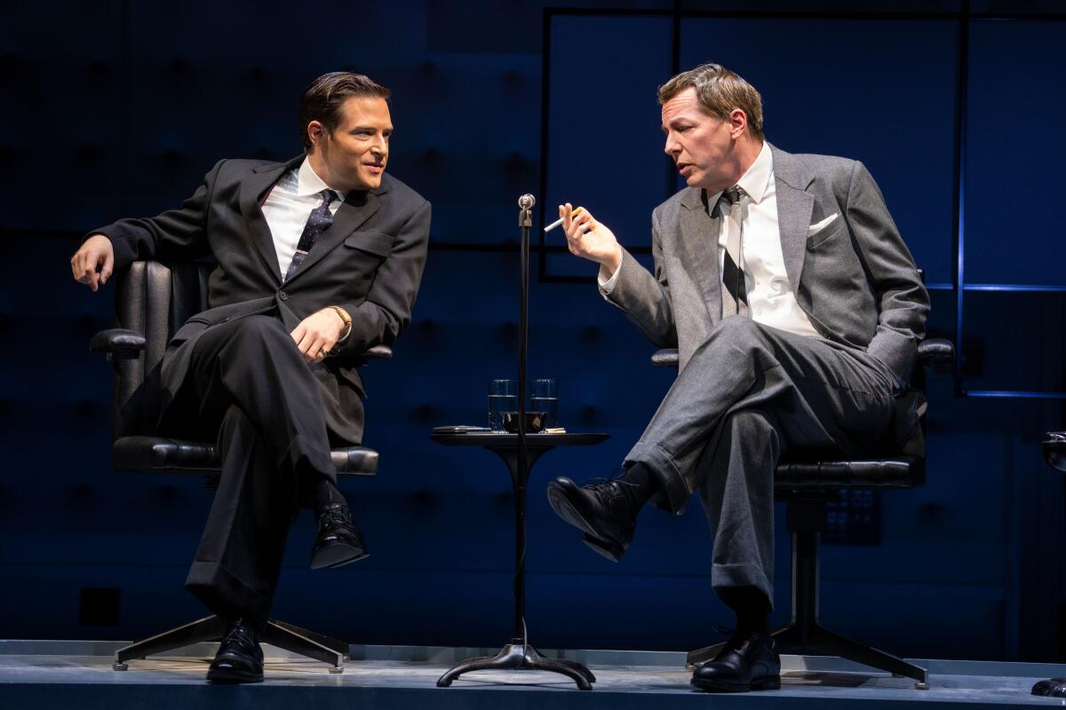 Two seated men in suits lean in to talk to each other in a scene from "Good Night, Oscar."