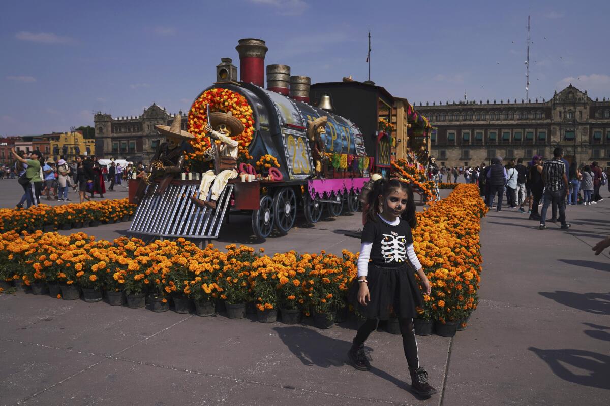 Personas posan para las fotos cerca de una exhibición por el Día de Muertos en el Zócalo, 