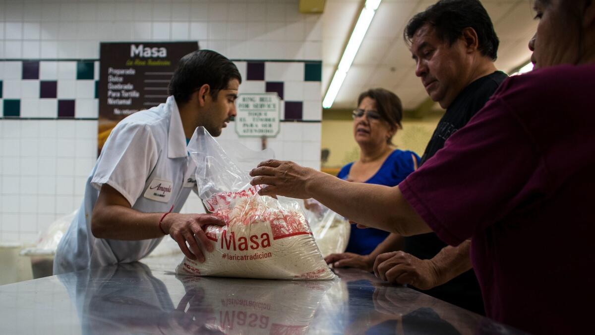 Grocery store clerk Hector Esparza hands out masa to customers at Amapola Market in Downey. Last Christmas, numerous customers returned masa purchased at Amapola seeking refunds.
