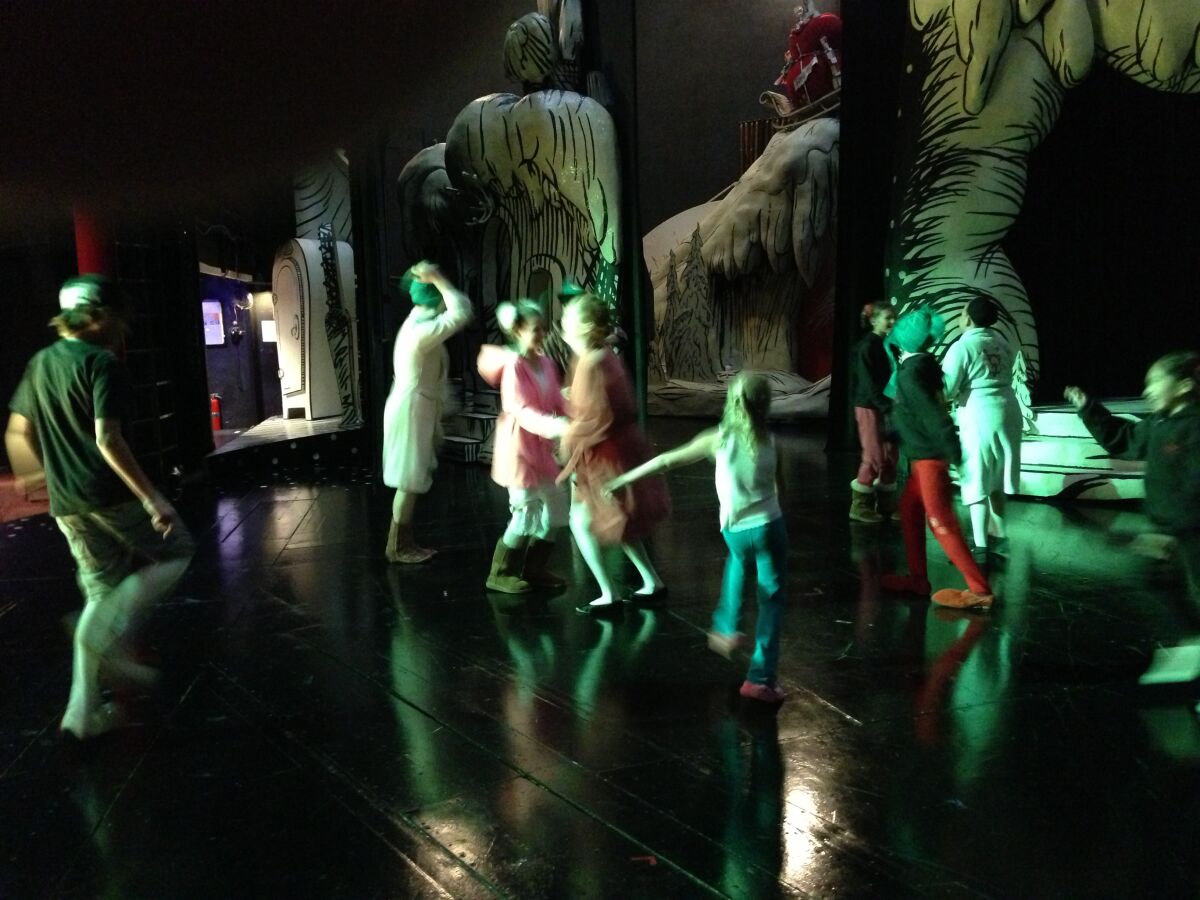 Children in the Old Globe's "Dr. Seuss's How the Grinch Stole Christmas" musical dance backstage among the scenery.