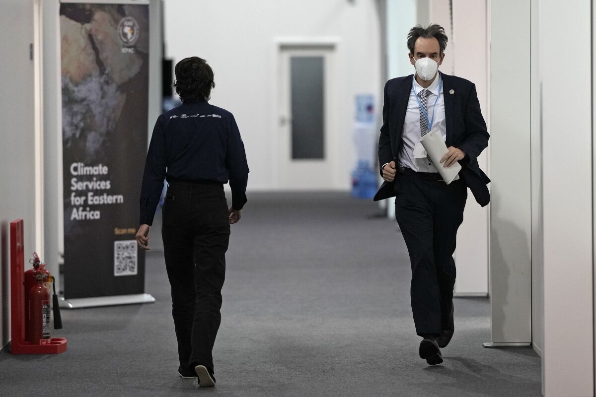Luxembourg negotiator Andrew Ferrone runs inside the venue of the COP26 U.N. Climate Summit in Glasgow, Scotland, Friday, Nov. 12, 2021. Negotiators from almost 200 nations were making a fresh push Friday to reach agreements on a series of key issues that would allow them to call this year's U.N. climate talks a success. (AP Photo/Alastair Grant)