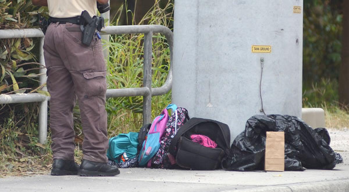 A police investigator photographs school backpacks taken off a school bus after a child was shot in Homestead, Fla.