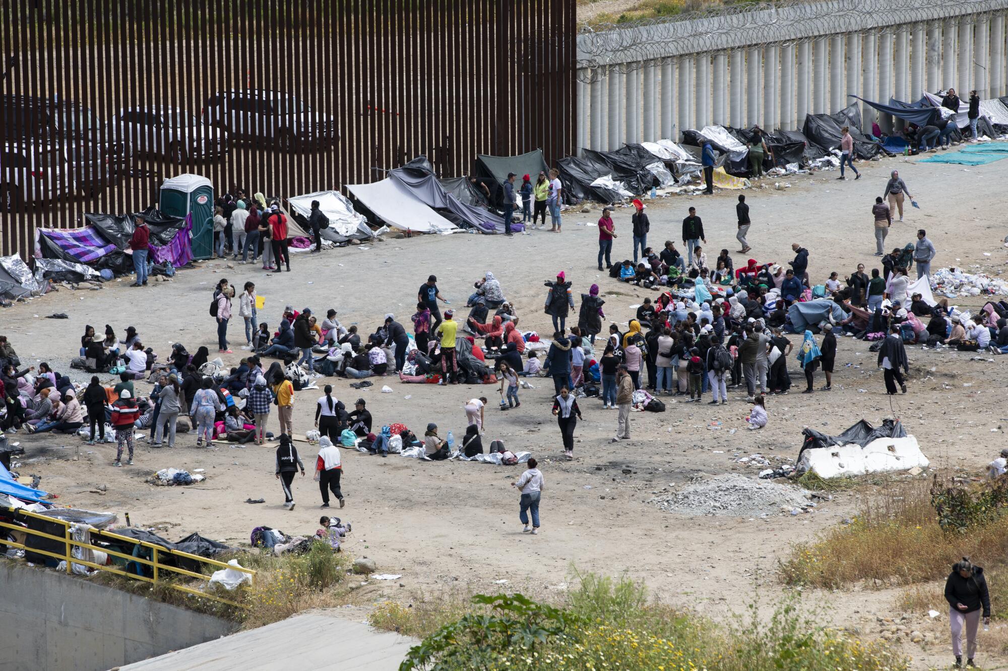 Hundreds of migrants wait between the U.S.-Mexico border walls a day before Title 42 is set to end.