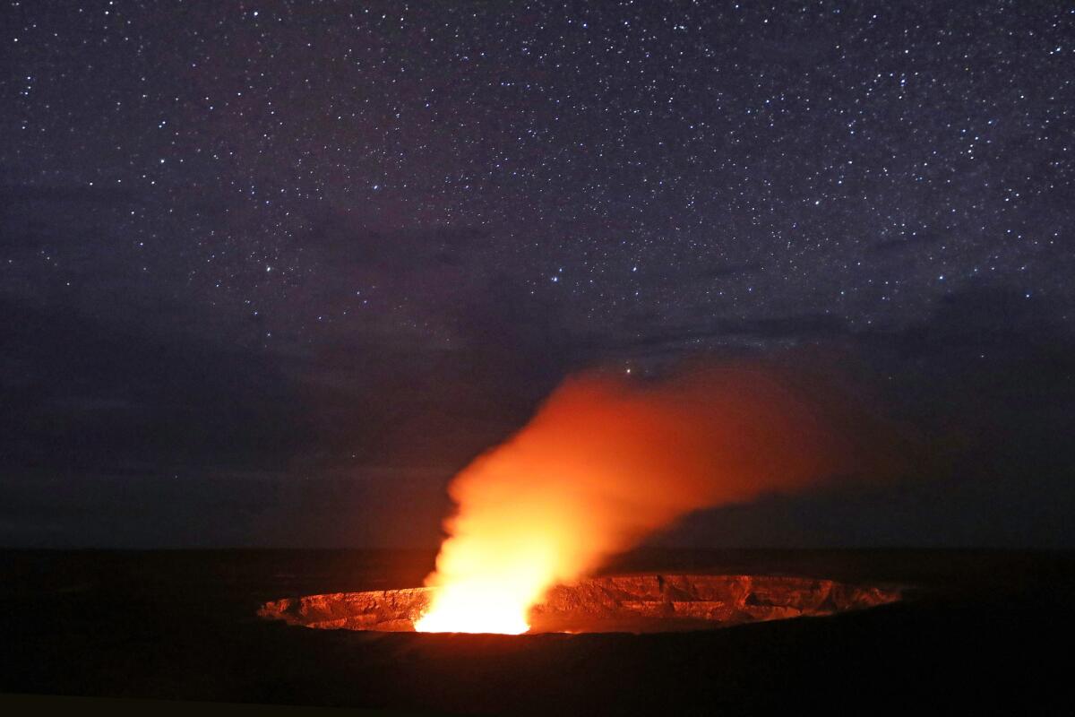 Stars shine above as a plume rises from the Halemaumau crater, illuminated by glow from the crater's lava lake.