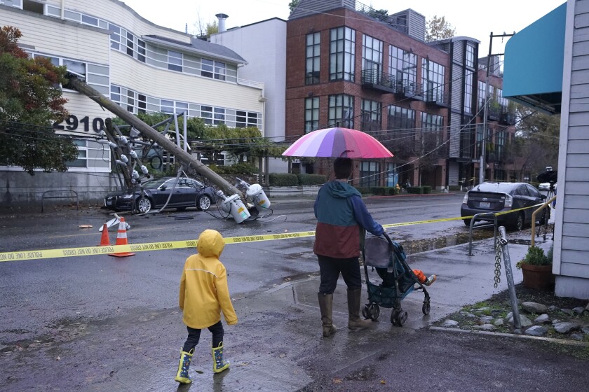People walk past a downed power pole blocking E. Madison St. in Seattle after it fell into an office building during a storm on Nov. 9, 2021. Seattle, a city known for soggy weather, has seen its wettest fall on record. The National Weather Service says 19.04 inches of rain fell in the period between Sept. 1 and Nov. 30, breaking a record set in 2006. (AP Photo/Ted S. Warren, File)
