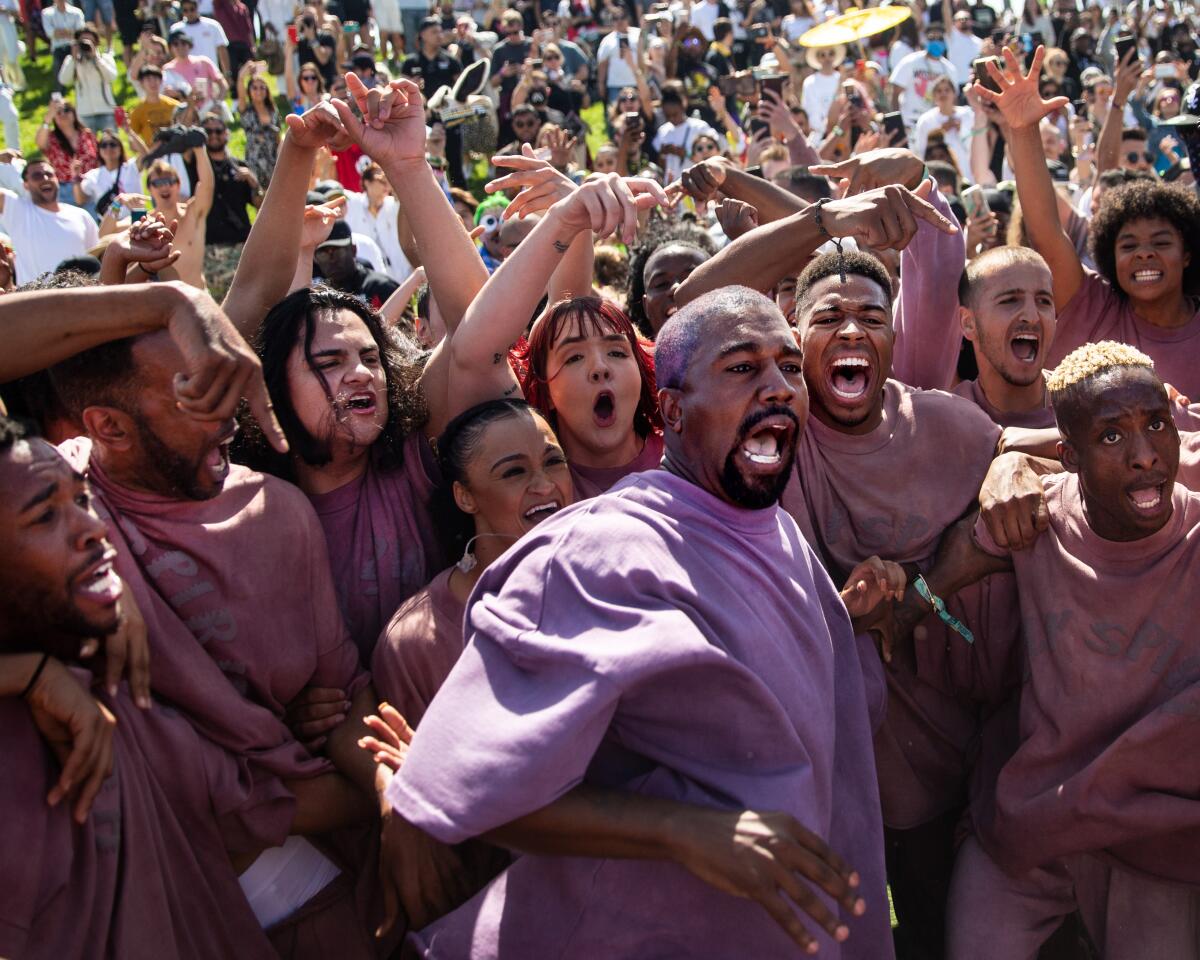 A man in purple sings while others in purple sing and crowd around him