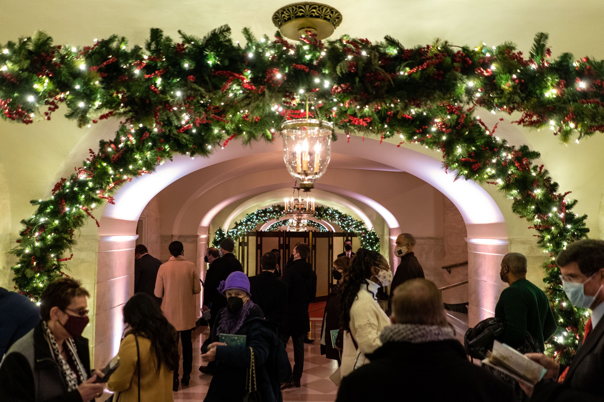 اعضای مردم در طول یک تور کریسمس در سالن مرکزی کاخ سفید پرسه می زنند.