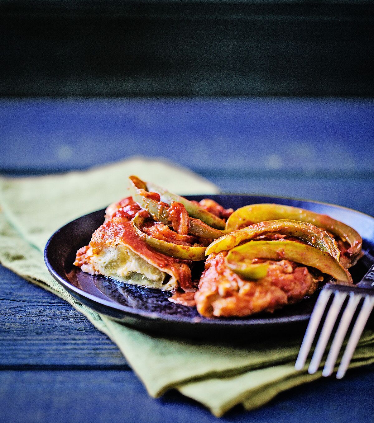 Chiles rellenos, Mexican cheese-stuffed peppers, covered in a tomato-based sauce with onions and bell peppers.