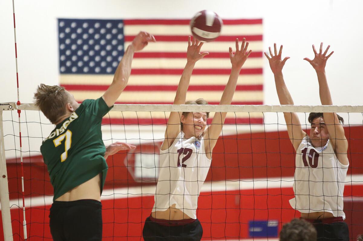 Laguna Beach blockers Geste Bianchi (12) and Tanner Mauro (10) get a piece of a shot by Edison's James Carpenter in a Sunset Conference crossover match on March 15.