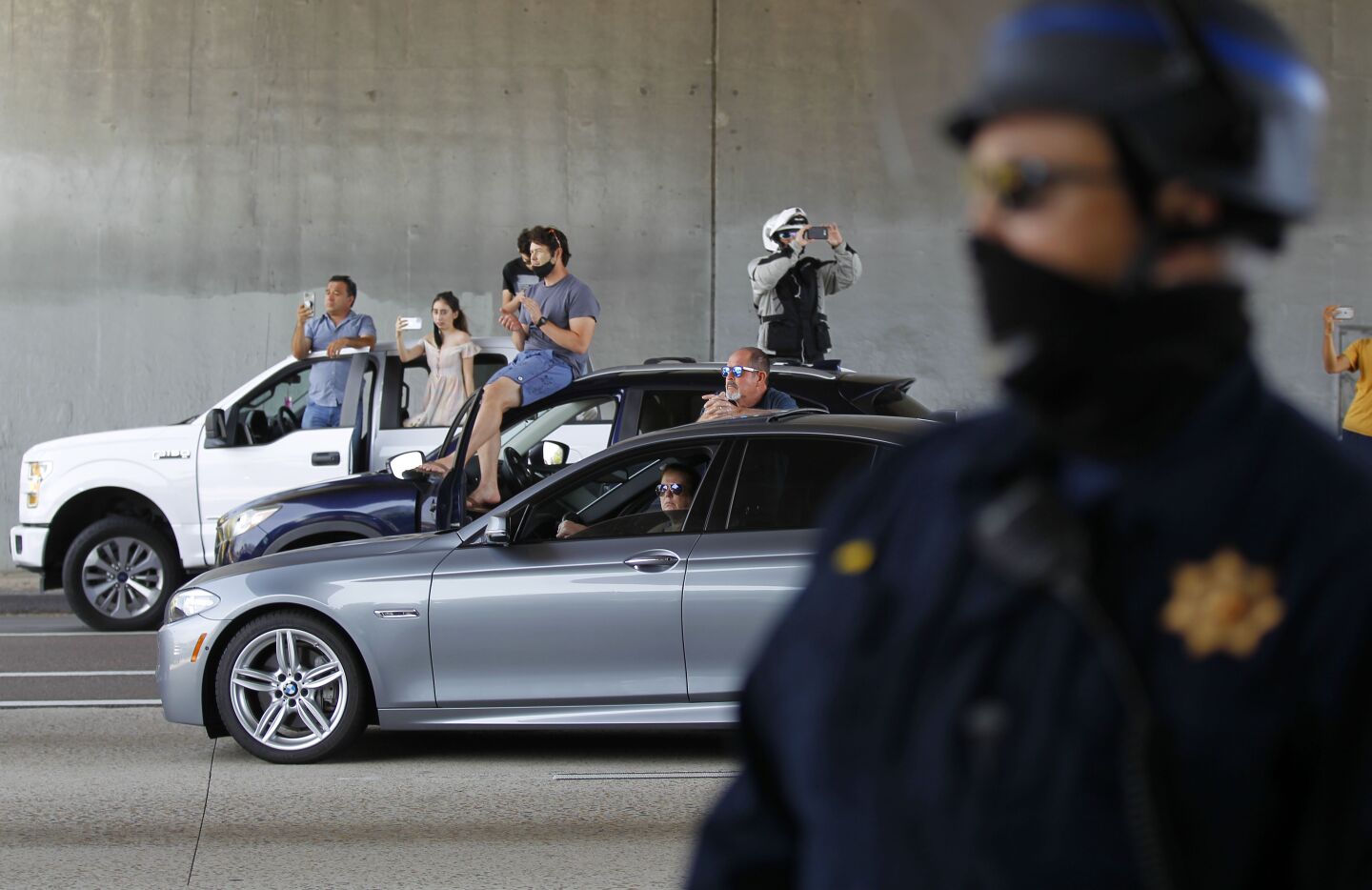 Pedestrians blocked on the freeway watch a group protesting the death of George Floyd march on I-5 in downtown San Diego on May 31, 2020.