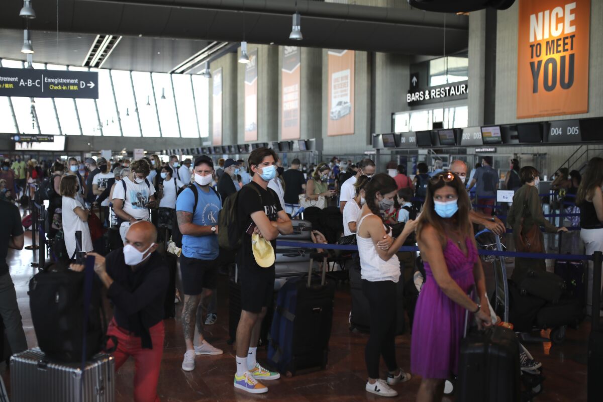 People queue in line to check-in for a British Airways flight to Heathrow airport, Friday Aug.14, 2020 at Nice airport, southern France. British holidaymakers in France were mulling whether to return home early Friday to avoid having to self-isolate for 14 days following the U.K. government's decision to reimpose quarantine restrictions on France amid a recent pick-up in coronavirus infections. (AP Photo/Daniel Cole)