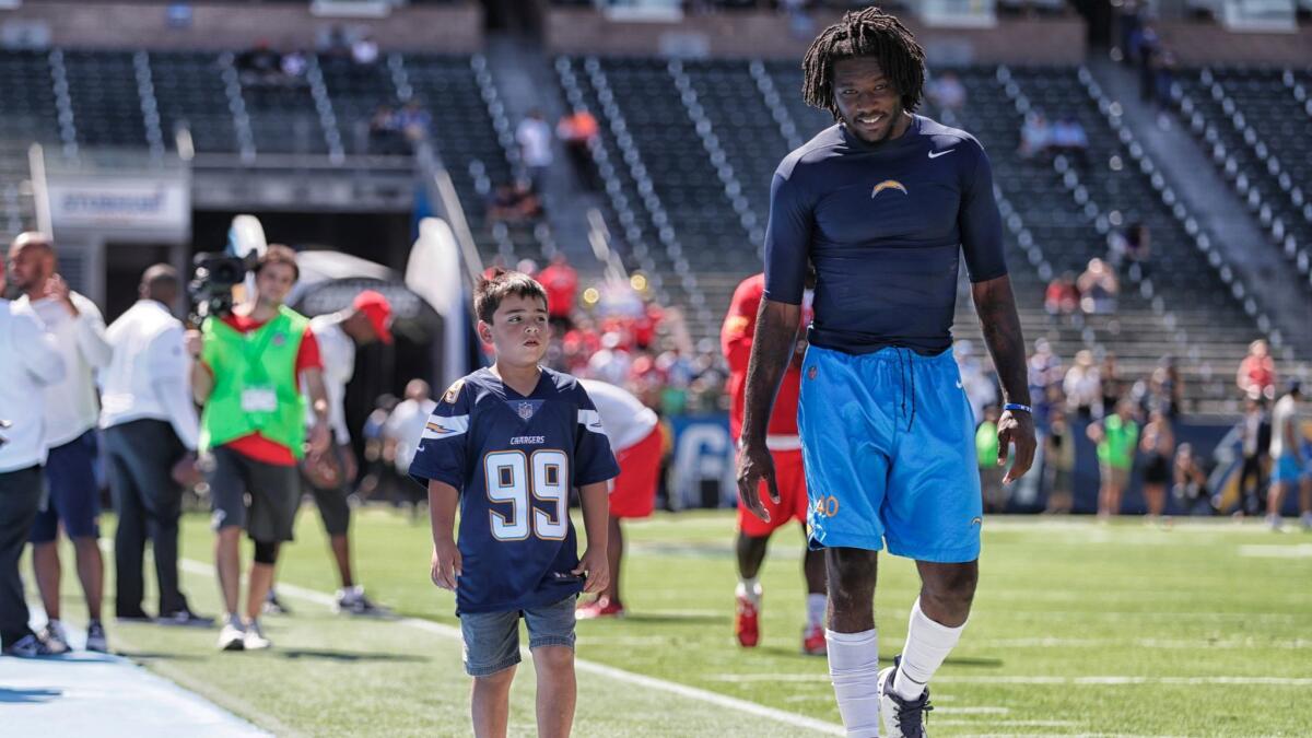 Chargers defensive end Chris McCain escorts Joshua Amaro-Anderson, 8, on a tour of the field before a game against the Chiefs at StubHub Center on Sept. 24.
