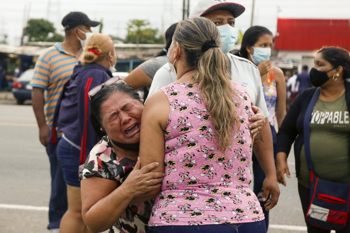 A sobbing woman embraces another woman