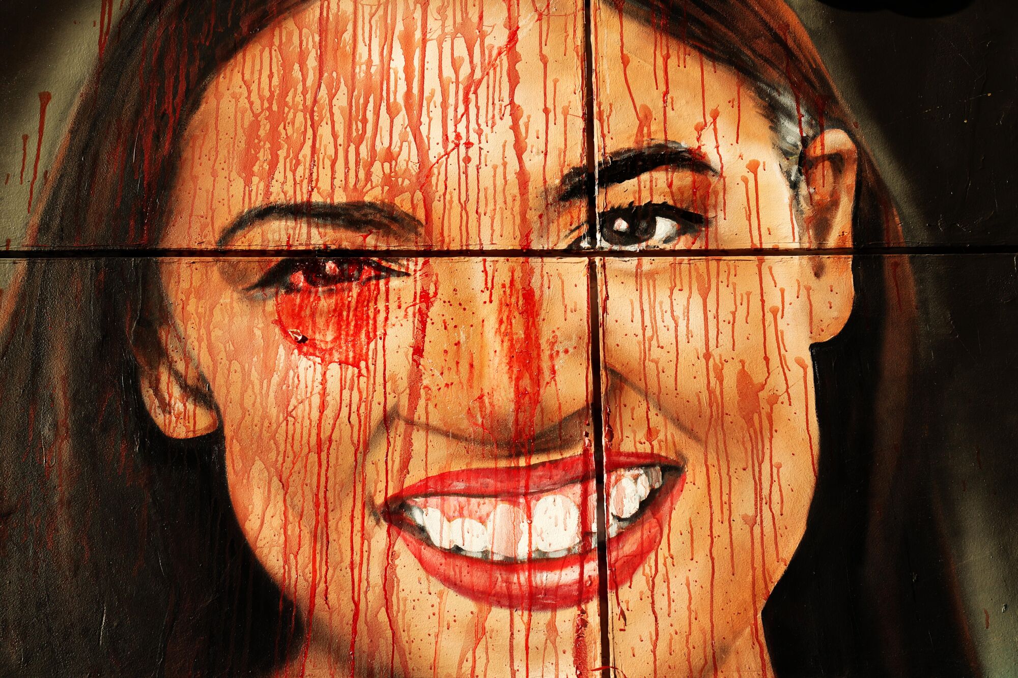 A mural of Alexandra Ocasio-Cortez with red paint splattered on it