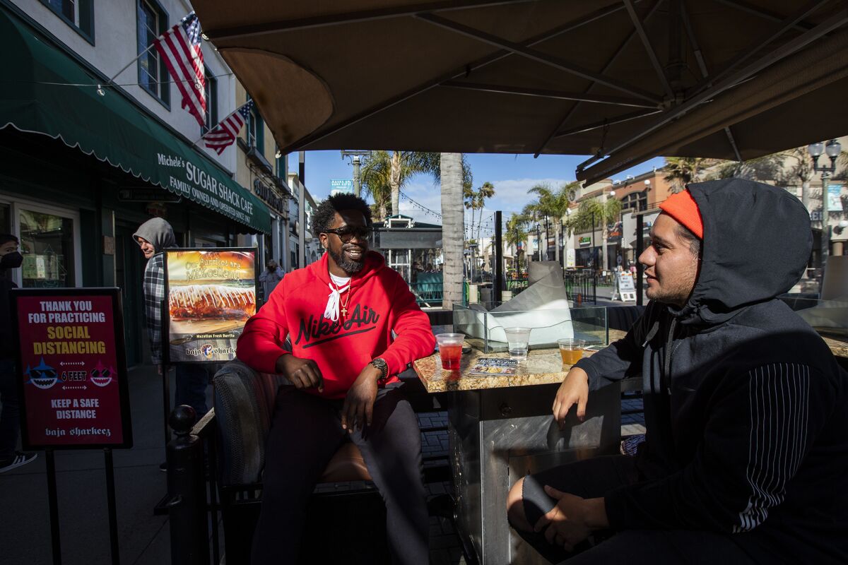 Michael Johson, left, and Adrian Garzon have a drink at Baja Sharkeez in Huntington Beach on Monday, March 15.