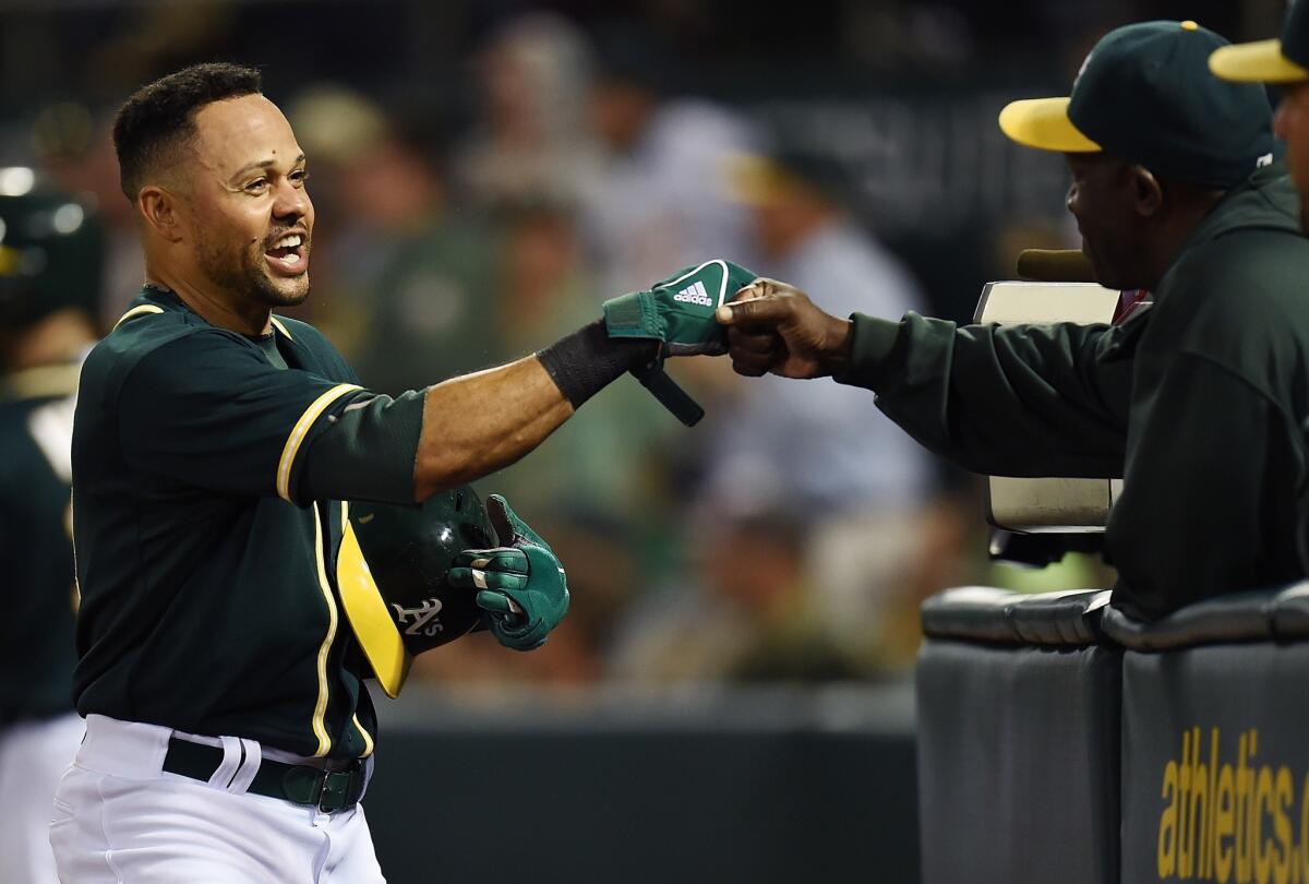 Oakland's Coco Crisp is congratulated by his hitting coach Chili Davis after scoring on a throwing error by the Angels' Erick Aybar in the sixth inning.