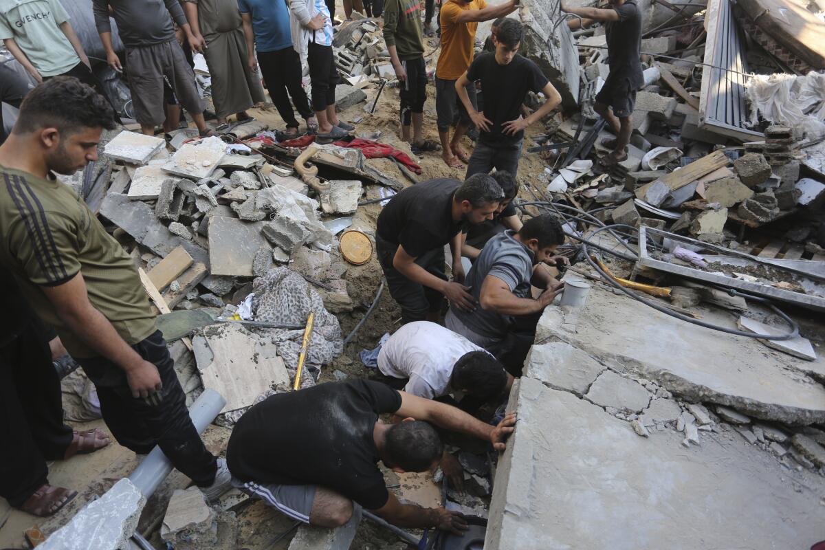 Palestinos buscan sobrevivientes entre los escombros tras un ataque israelí en Rafah, en la Franja