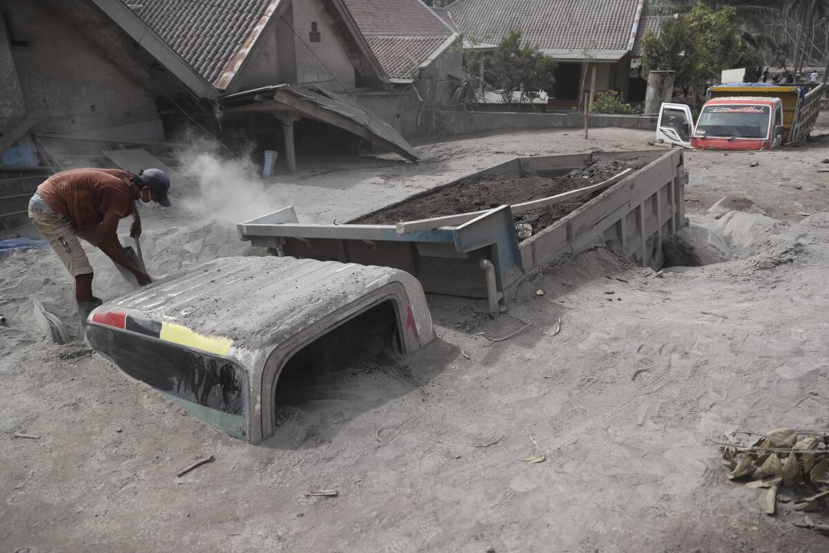 A man examines a truck that was buried in volcanic ash in Indonesia’s East Java province.