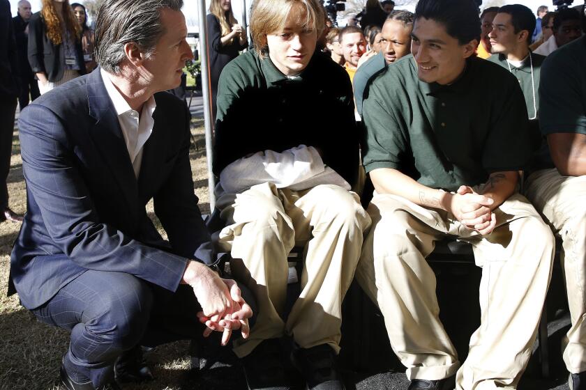 FILE - In this Jan. 22, 2019, file photo, Gov. Gavin Newsom talks with Juan Cruz Lopez Jr., far right, a youthful offender at the O.H. Close Youth Correctional Facility, in Stockton, Calif. Newsom signed a bill Wednesday, Sept. 30, 2020, that will phase out the state's remaining juvenile prisons, which currently hold about 750 youths, a move that Sen. Nancy Skinner called "monumental for juvenile justice in California." Counties would stop sending juveniles to state lockups after July 1. The state will instead create an Office of Youth and Community Restoration and send grants to counties to provide custody and supervision. (AP Photo/Rich Pedroncelli, File)