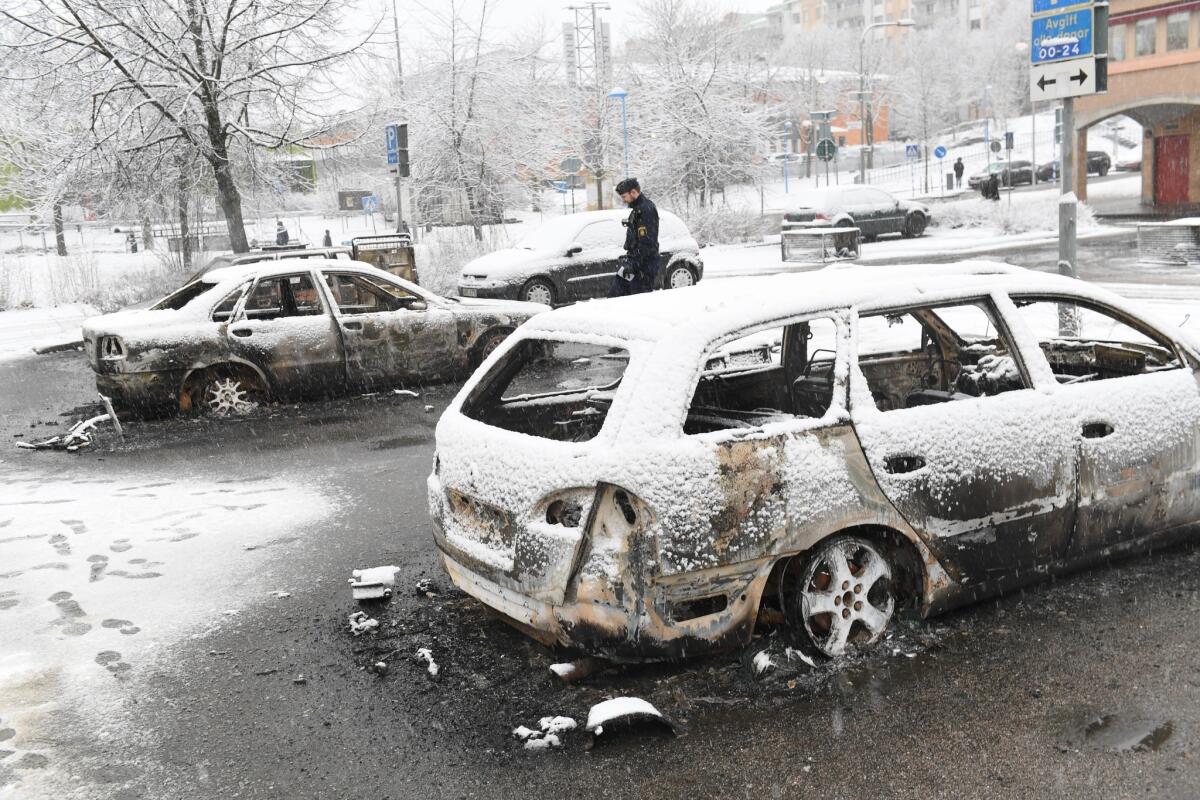 A police officer takes notes at a burnt car in the suburb of Rinkeby outside Stockholm, Sweden on Feb. 21.